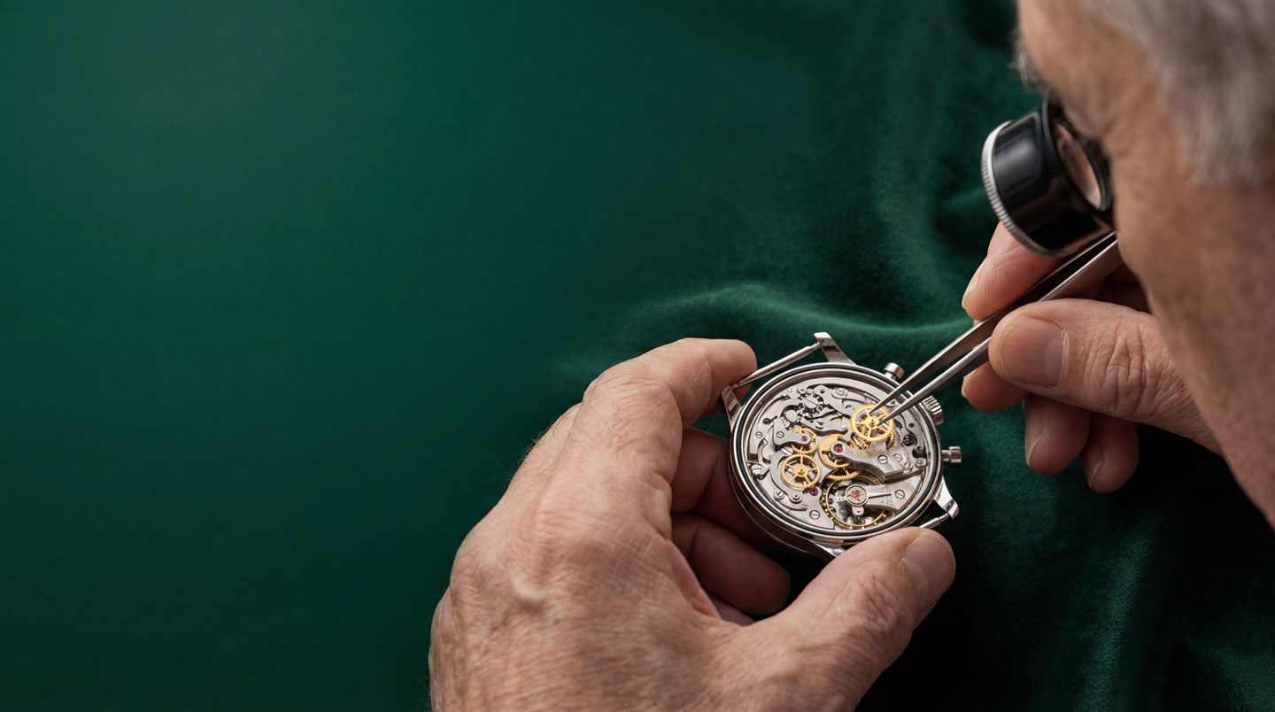 Atelier de manufacture horlogère indépendante française en Franche-Comté avec plusieurs horlogers assemblant mouvements mécaniques à leurs établis sous lumière naturelle